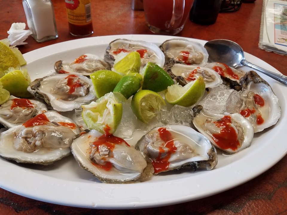 Fresh seafood dishes beside beer glasses.